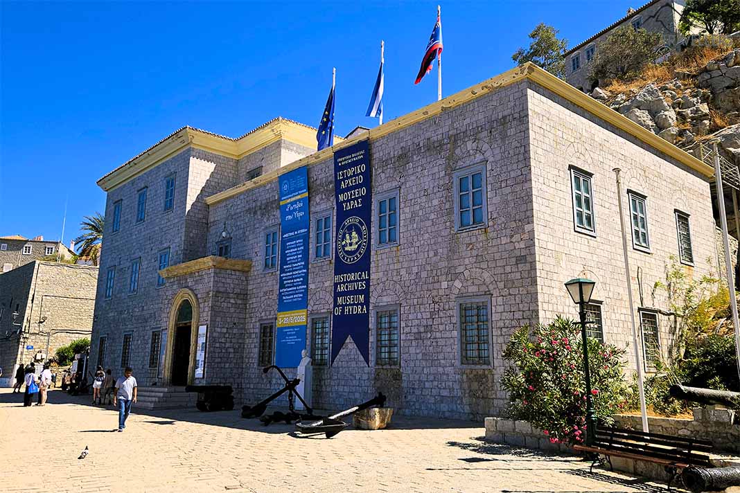 Das zweistöckige Steinhaus mit den blauen Bannern beherbergt das Historische Archivmuseum von Hydra