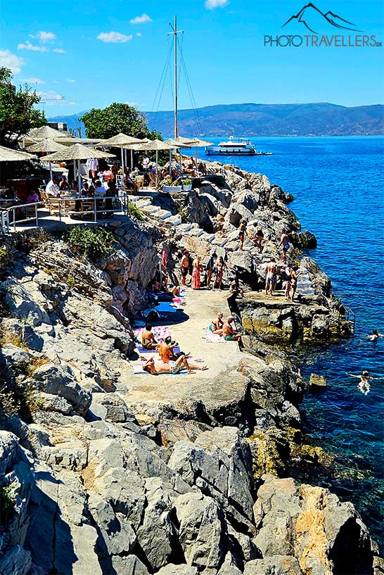 Badegäste liegen auf den Felsvorsprüngen am Spillia-Beach