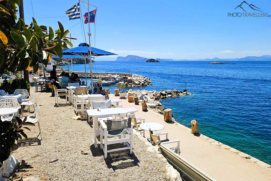 Weiße Tische und Stühle einer Taverne säumen die Promenade von Kaminia