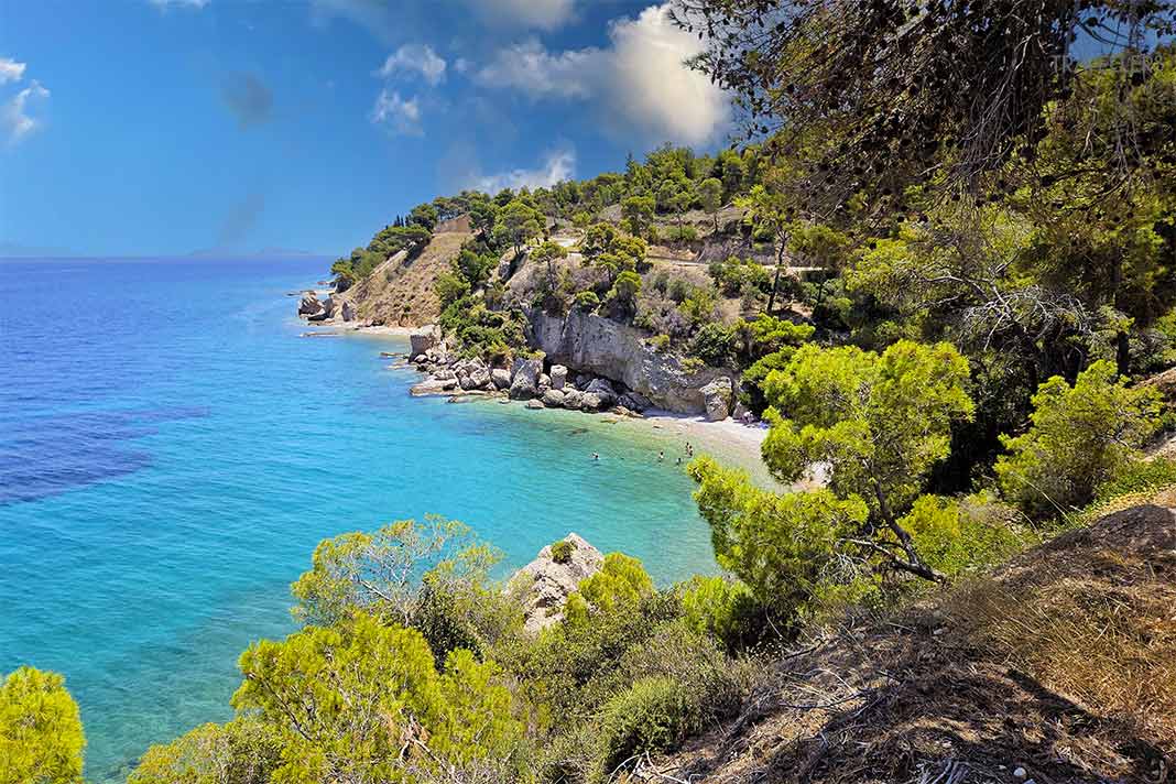 Eine mit Bäumen bewachsene Felsbucht mit türkisblauem Meer