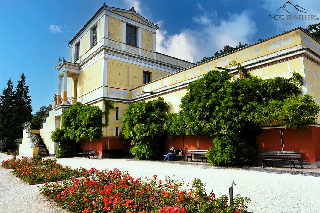 Die mehrstöckige römische Villa Pompejanum ist umsäumt von Pflanzen und roten Blumen