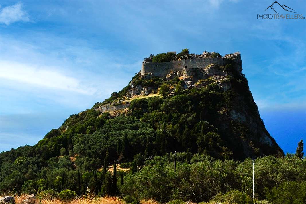 Die Ruine Angelokastro erhebt sich auf einem bewaldeten, kegelförmigen Berg