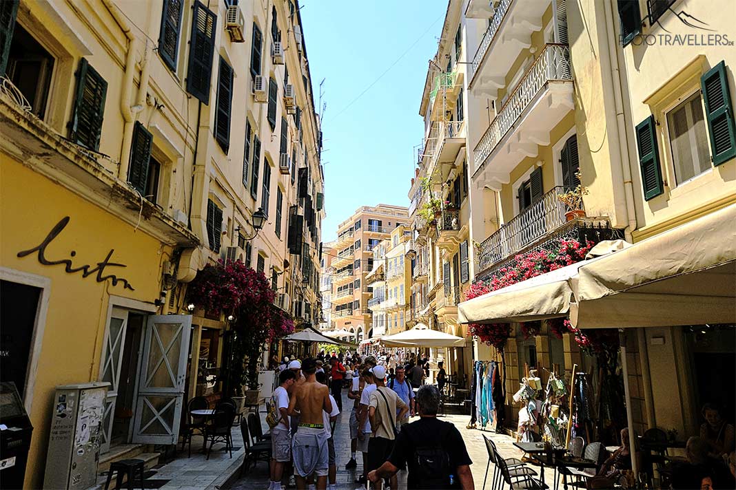 Viele Menschen flanieren durch die mit gelben Fassade umrahmten Altstadtgassen in Kerkyra