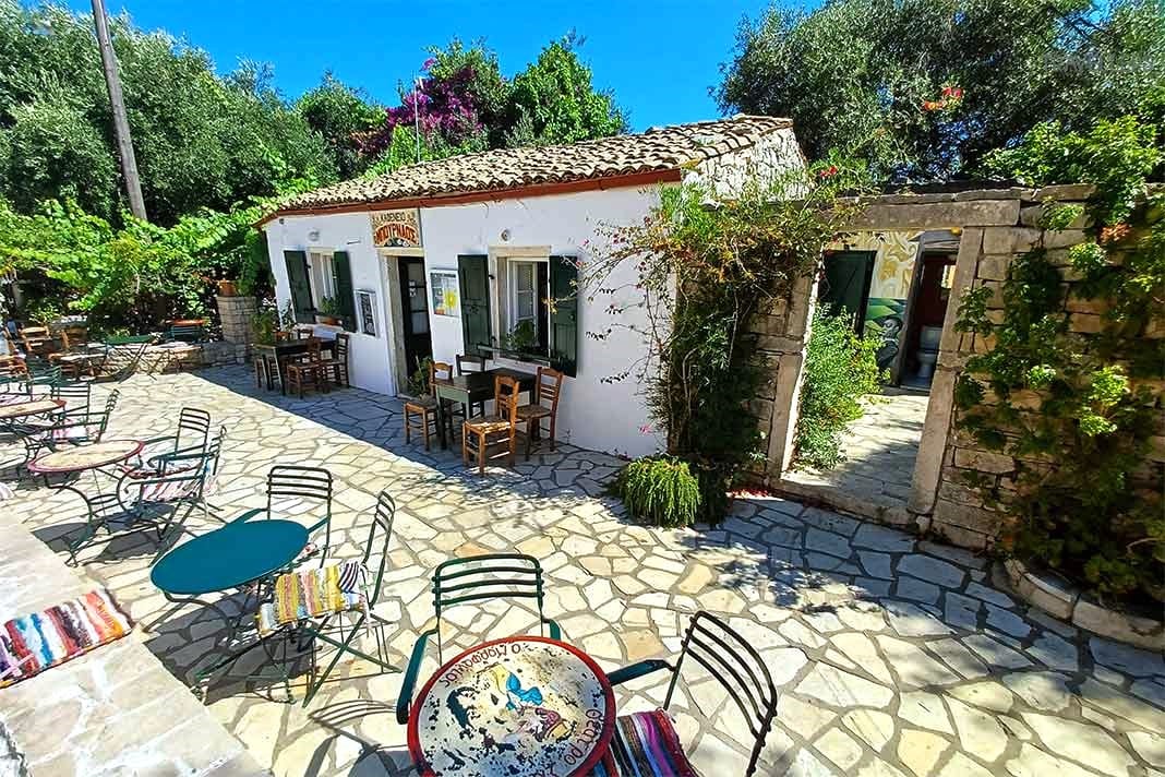 Bunte Tische und Stühle stehen auf der Steinveranda vor der Taverne Bournaos in Maratia