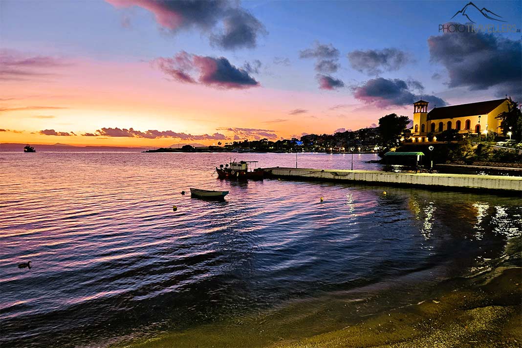 Sonnenuntergang mit einer beleuchteten Kirche in der Bucht von Neos Marmaras