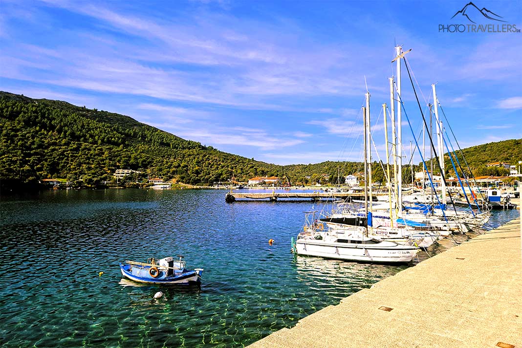 Mehrere Segeljachten und ein kleines Fischerboot ankern an der Promenade von Porto Koufo