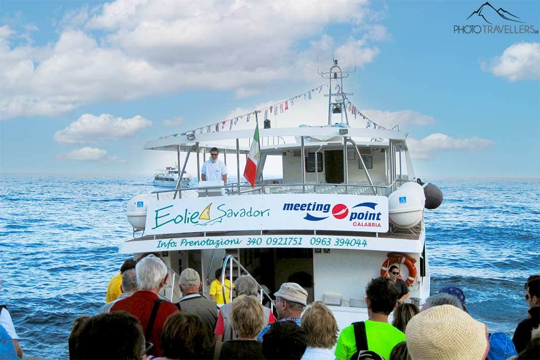 Etliche Menschen stehen am Hafen und warten auf den Zutritt zu einem weißen Ausflugsboot
