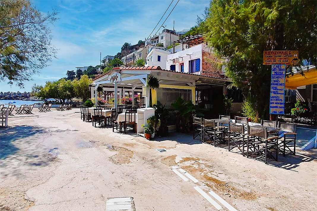 Eine überdachte Terrasse einer Taverne in Therma mit wenigen Gästen an den Tischen