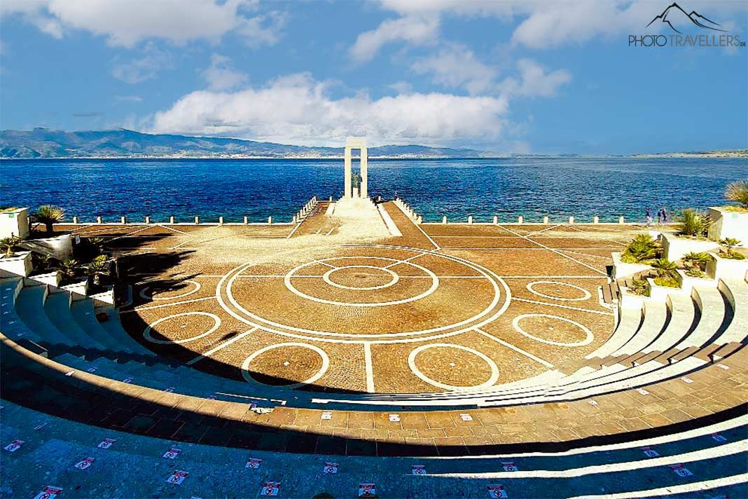 An der Promenade von Reggio Calabria liegt ein kleines Amphitheater mit hellbrauen Steinen und einer weißen Marmorsäule in der Mitte