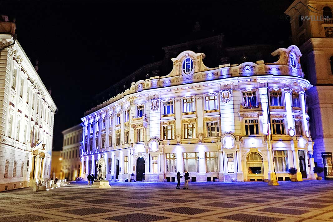 Das historische Rathaus bei Nacht mit einer violetten Farbgebung mit Teilen des beleuchteten Brukenthal-Palais
