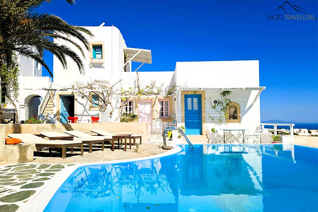 Der weiße Bungalow der Hotel Ampelos mit Pool und Palmen im Sonnenlicht