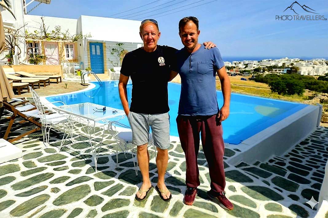 Zwei mittelalte Männer in Umarmung stehen vor einem Pool auf Folegandros