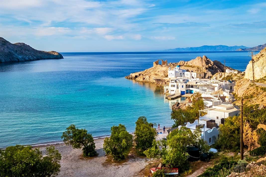 Die Bucht von Firopotamos mit der kleinen Siedlung und der Kapelle am Rand im Sonnenlicht