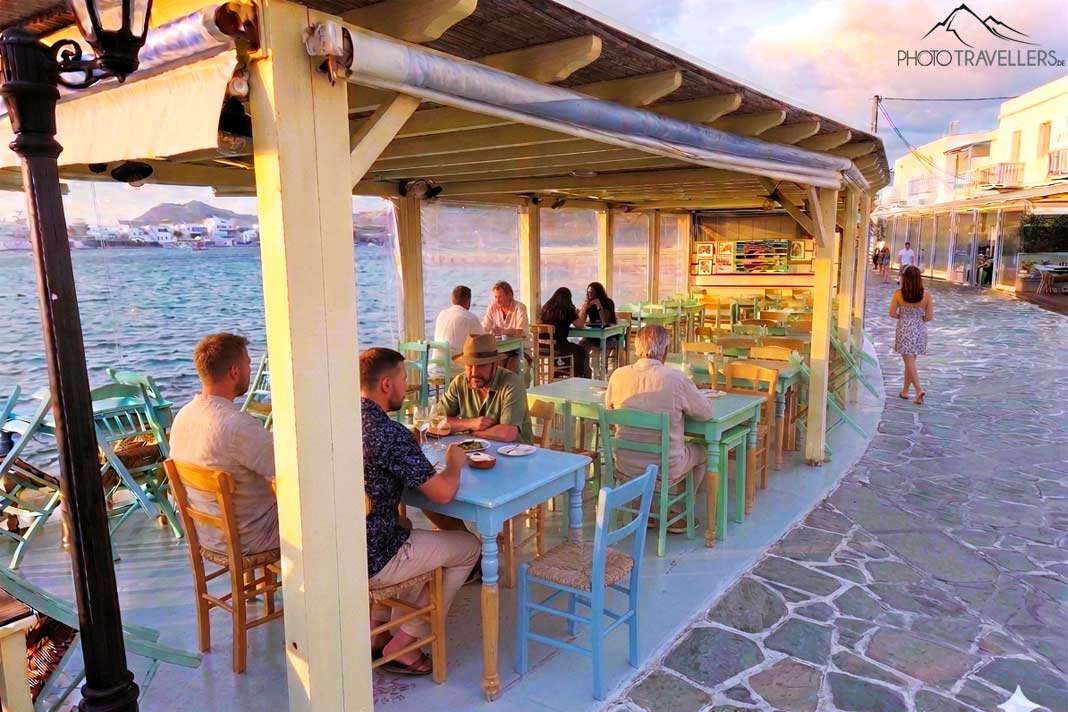 Gäste sitzen in einer überdachten Veranda an der Promenade von Pollonia