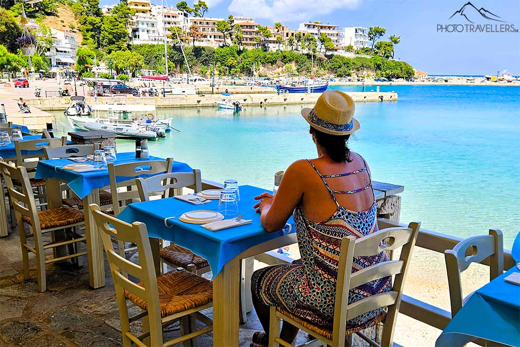 Eine Frau sitzt in einer Taverne und schaut auf den Hafen von Patitiri auf Alonnisos