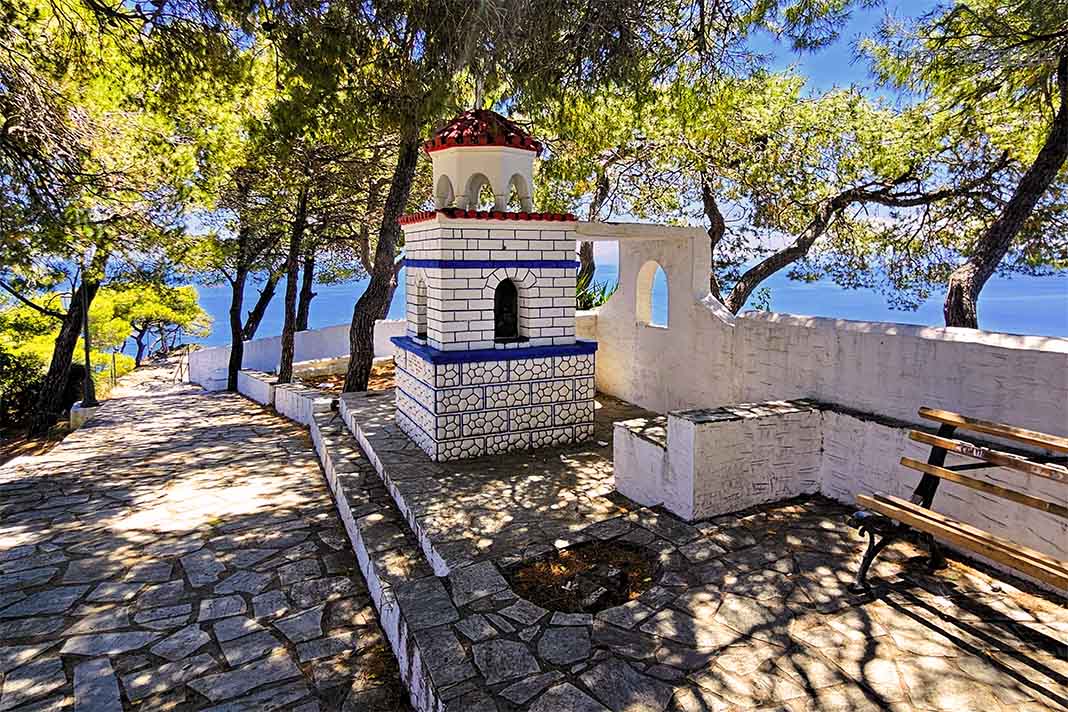 Ein gemauerten Schrein mit Kuppel unter Bäumen am Meer in Plakes