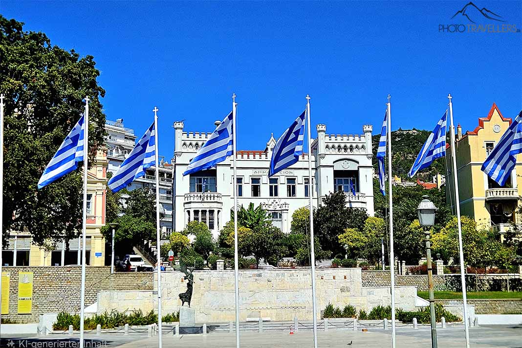 Mehrere Masten mit Griechenlandflaggen wehen vor dem weißen, zweistöckigen Rathaus von Kavala