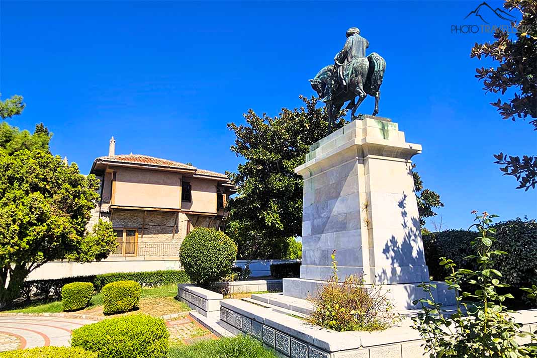 Reiterdenkmal für Muhammed Ali Pascha auf einem Marmorsockel neben dem zweistöckigen Geburtshaus mit hellroter Fassade