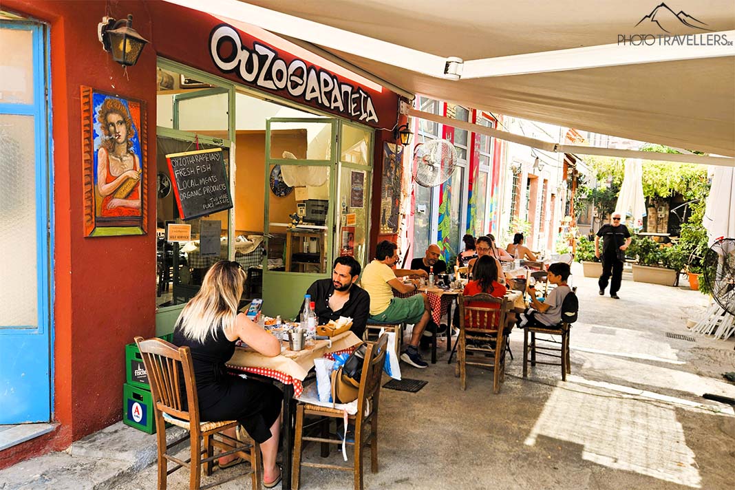 Menschen sitzen an den Tischen einer Taverne mit roter Fassade