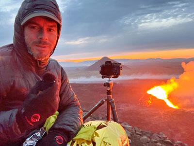 Profi-Fotograf Florian Westermann mit Kamera vor einem brodelnden Vulkan in Island